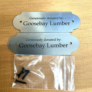 Metal plaque and screws on a wooden surface with 'Goosebay Lumber' branding.