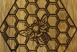Wooden surface with laser-engraved honeycomb pattern and bee
