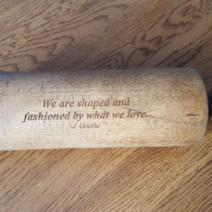 Wooden rolling pin with engraved quote on a wooden surface